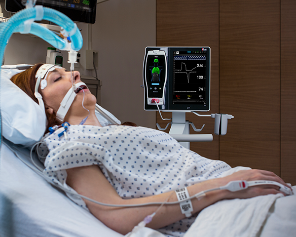 Schlafender intubierter Patient in einem Krankenhausbett wird mit einem Fingersensor mit Root und Radical-7 überwacht.