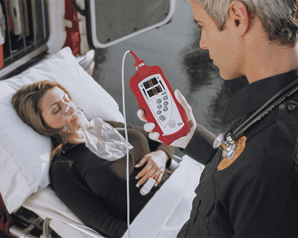 Sanitäter überwacht einen bewusstlosen Patienten auf einer Trage neben einem Rettungswagen.