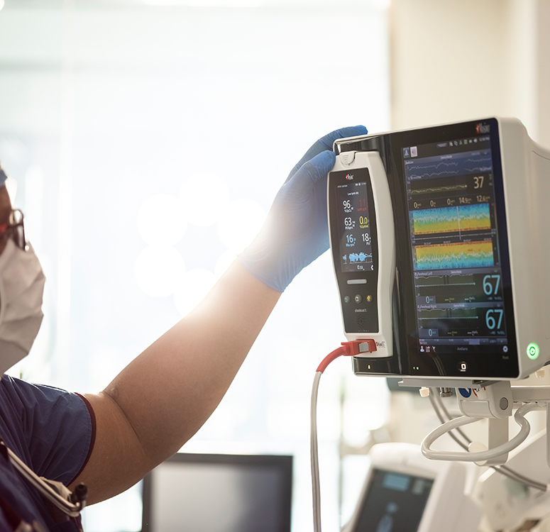 Gesundheitsfachkraft interagiert mit einem Masimo-Patientenüberwachungssystem, das erweiterte Vitalzeichen-Trends anzeigt.