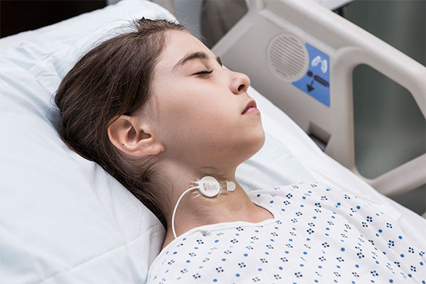 Masimo - Kind im Krankenhausbett trägt Sensor für akustische Atemfrequenz (RRa) am Hals